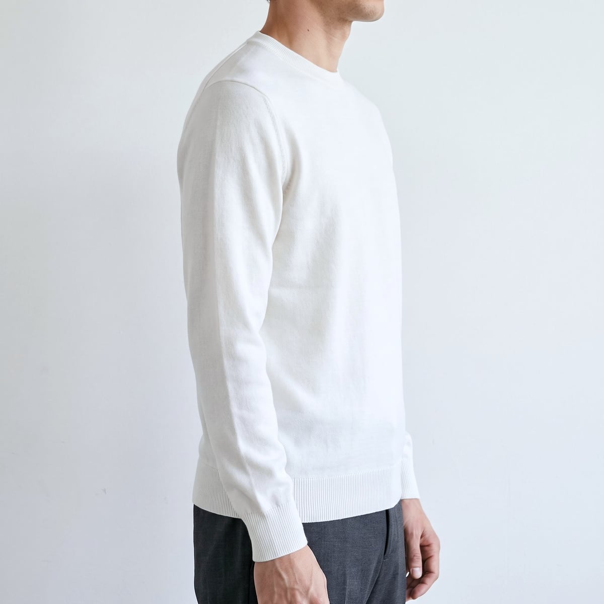 白いニットを着た男性を真横から。袖口と裾のリブがすっきり収まっている