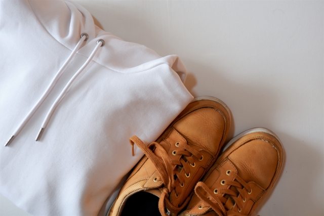 畳んだ白のパーカーとブーツ