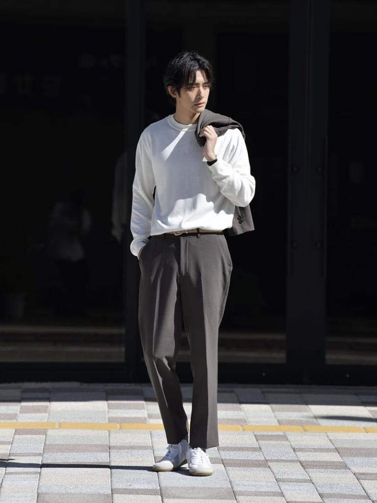 オフホワイトのニットとブラウンスラックスのコーデ