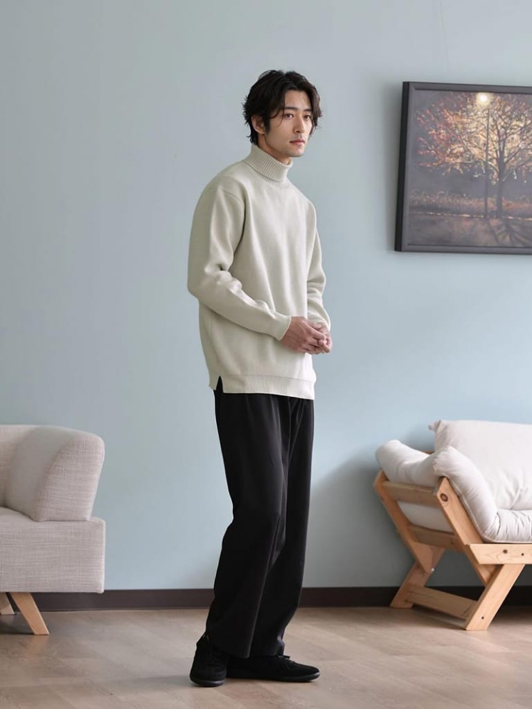 アイボリーのタートルネックニットとブラックパンツのコーデ